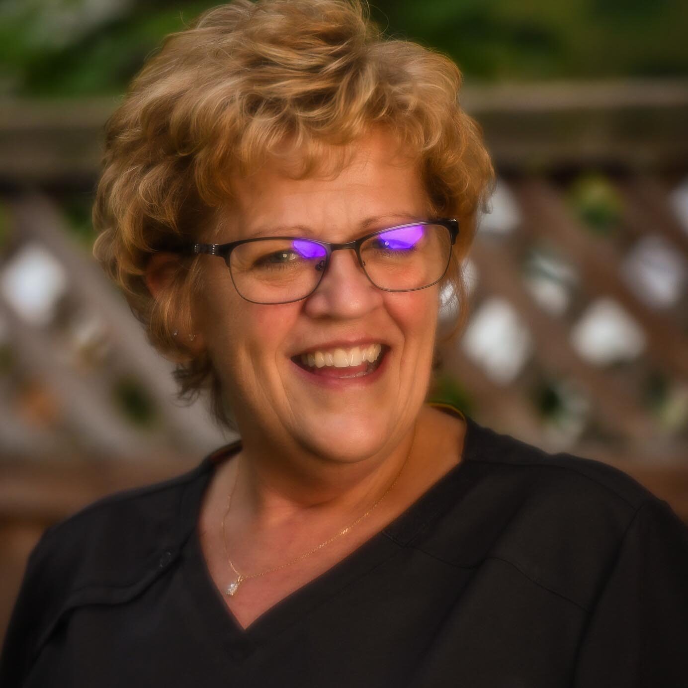 A woman with glasses and a black shirt smiling, radiating warmth and confidence. She is Julie, Scheduling and Insurance Coordinator at Clinton Family Dental.